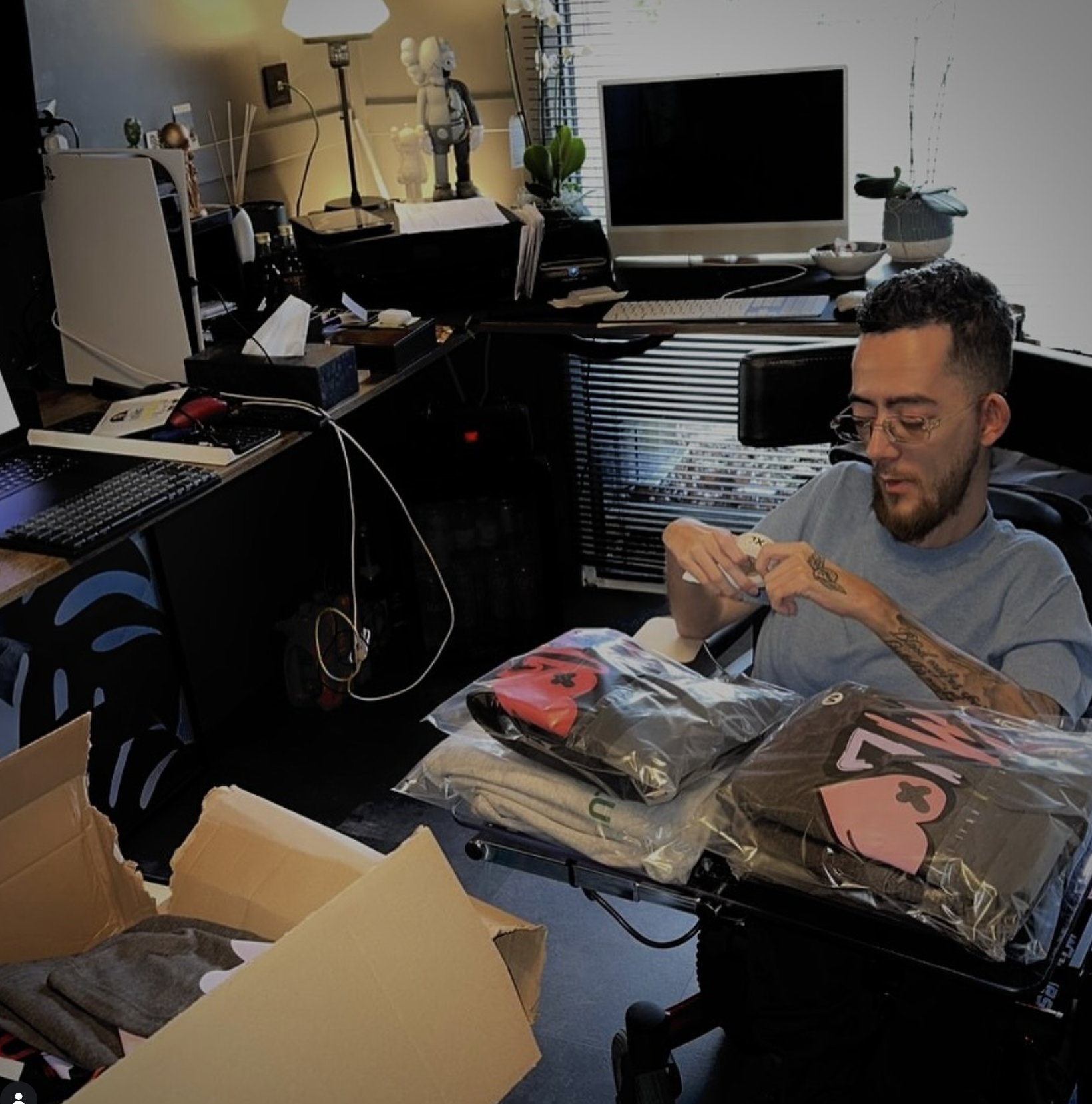 Adam thuis tussen dozen en verpakte QMLH-kleding, kort na de oprichting van de stichting